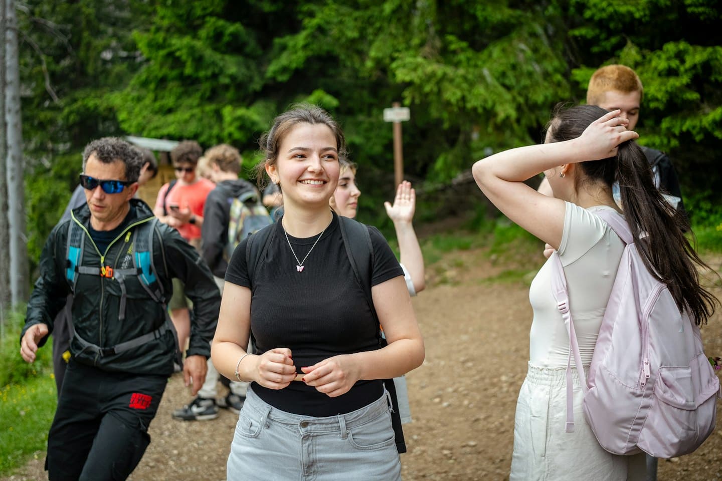 Un grupo de excursionistas camina por un sendero de tierra en el bosque.
